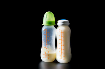 Baby bottle with breast milk on black background