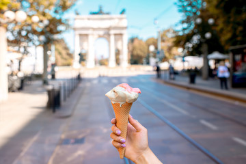 Holding colorful ice cream in the waffle cone on the city street background in Milan