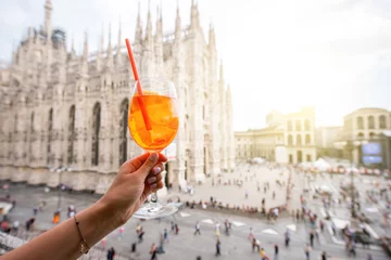 Deurstickers Holding a glass of spritz aperol drink on the main square with Duomo cathedral on the background in Milan city © rh2010