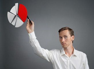 Man in white shirt working with pie chart on grey background.