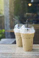 two of take away iced coffee cup put on a wooden table at coffee cafe. blurred background.selective focus