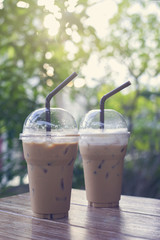 two of take away iced coffee cup put on a wooden table at coffee cafe. blurred background.selective focus