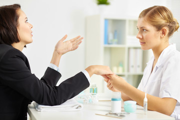 Businesswoman visiting manicurist and talking to her