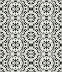 Black and white monochrome seamless pattern background made of repeating scanned elements of handmade crochet lace