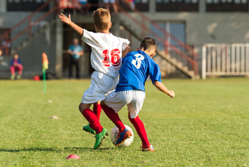 Boys playing football soccer game on sports field