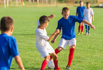 Boys playing football soccer game on sports field