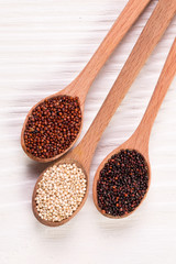 Red, black and white quinoa seeds on a wooden background