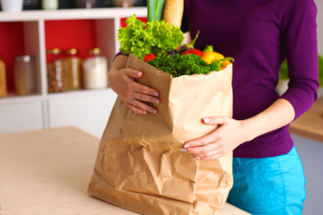 Healthy positive happy woman holding a paper shopping bag full of fruit and vegetables