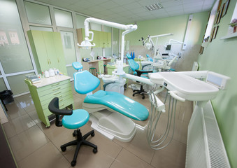 Dentist chairs with modern equipment at bright treatment room in dental clinic