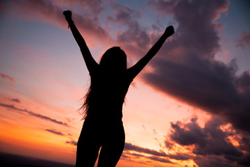 Fototapeta premium woman gesturing success - silhouette over evening sky