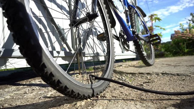 Pumping up bicycle wheel outdoor, closeup
