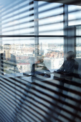 Business people communicating behind blinds