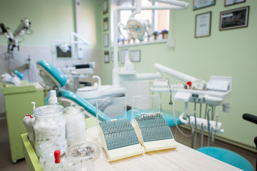 Different dental burs, polishing heads and supplies on the stand near dental unit in a modern dental office