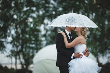 Happy newlyweds under the white umbrella