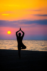 man practices yoga on the beach, the sea.