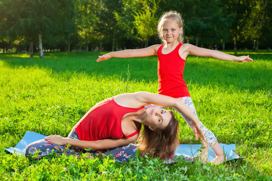 Mother and her daughter outdoors doing yoga
