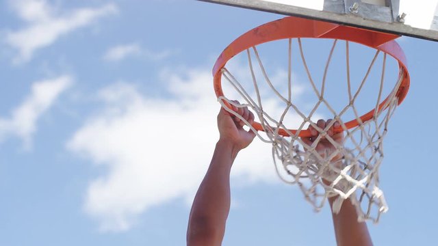 Close up of basketball player's hands slam dunking, in slow motion