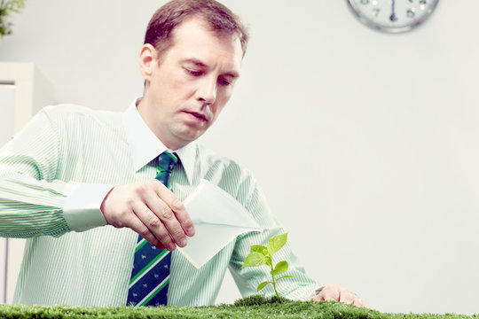 Businessman Watering Plant In Office