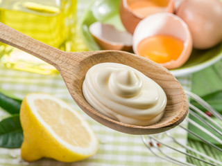 Natural mayonnaise sauce in the wooden spoon and its ingredient