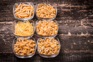 Various mix of pasta on wooden rustic background. Diet and food