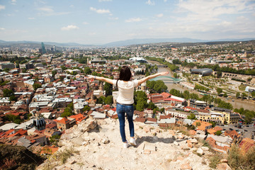 The girl is staying on the edge and watching the city of Tbilisi, Georgia.