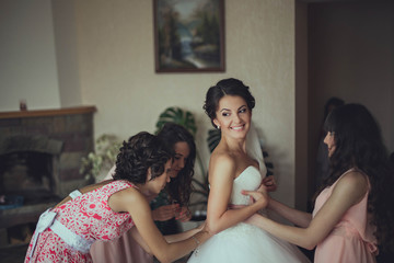 bridesmaids  helps the bride dress wedding dress