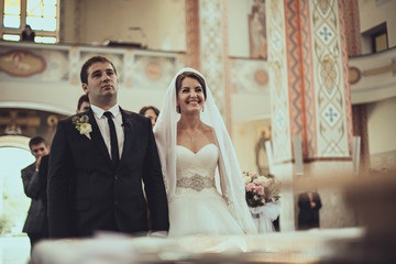 groom and his bride smiling to the priest