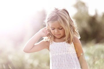 Naklejka premium Portrait of cute little blond girl in countryside, summertime