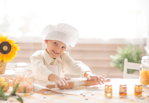 little boy in the form of a cook rolls out the dough