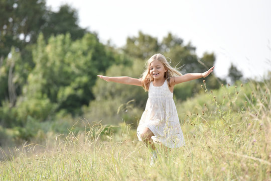 Little girl running in country field in summer