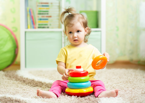 cute baby playing with colorful toy at home