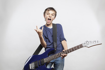 Fototapeta premium Portrait of adorable young boy playing electric guitar. kid show