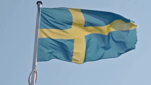 Waving Swedish flag on a blue summer sky, retro film toned