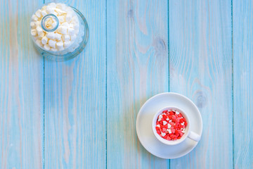 Coffee cup full of candies flat lay on rustic light blue wooden background
