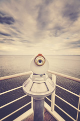Retro toned picture of a telescope pointed at horizon, shallow depth of field, future concept.