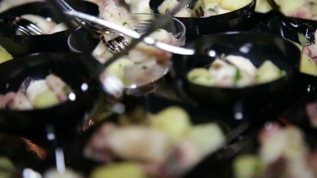 Antipasto di pesce con polipo e patate al cucchiaio dentro ciotole di plastica nere e bianche servite a un buffet di un matrimonio