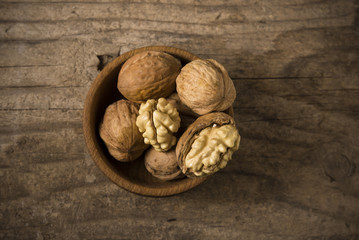 Walnut kernels and whole walnuts on rustic old wooden table
