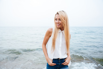 Cheerful woman with long blonde hair standing on the beach