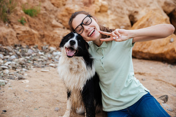 Cheerful pretty young woman hugging her dog on the beach