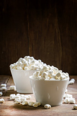 Marshmallow in white bowls. Vintage wooden background. Selective
