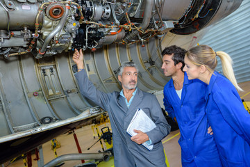 engineering teacher checking airplane engines with his students
