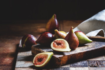 Cut purple figs on the board. Vintage wooden background, low key