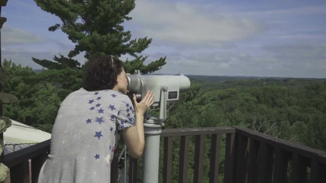 Woman in the mountains looks through telescope