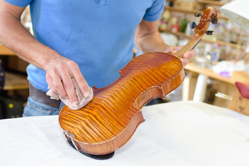 Man polishing back of a violin