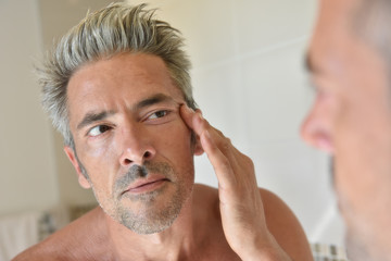 Mature man in front of mirror applying cream