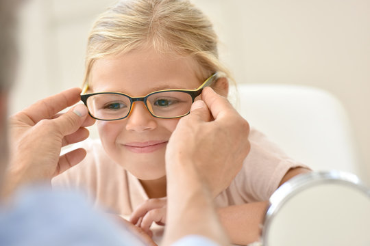 Little girl at the optician trying different eyeglasses