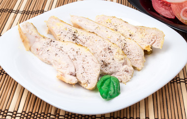Sliced fillets of baked chicken on a white plate