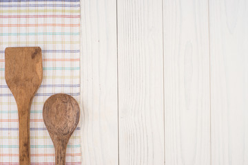 Wooden spoon and spatula on a napkin and an old white wooden tab