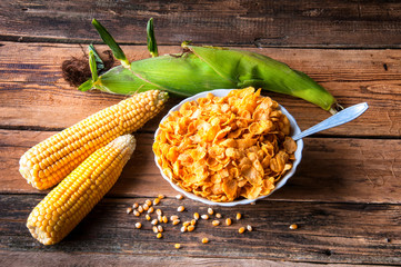 Fresh corn with corn flakes on wooden background