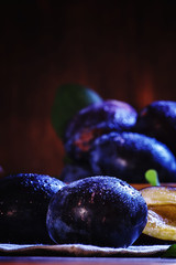 Blue plums with leaves. Wooden bowl with fruit. Rustic style, lo